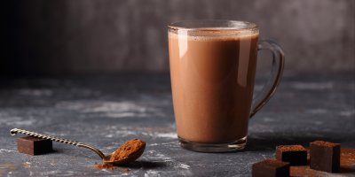 Horká čokoláda ve skleněném hrnku, instantní směs na lžičce, kousky čokolády