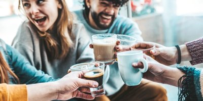 Skupina lidí si přiťukává hrníčky s kávou