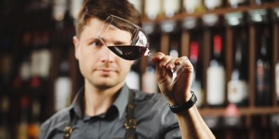 Barman si prohlíží červené víno ve sklenici