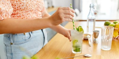 Žena drží sklenici a brčko na stole