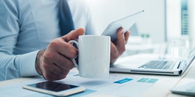 Člověk sedí v kanceláři a drží bílý hrnek