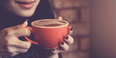 Žena drží červený hrnek s kávou