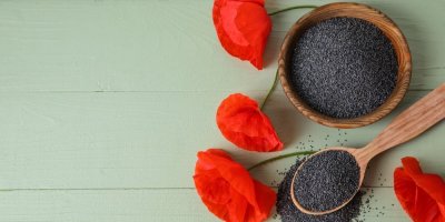 Semínka máku v dřevěné misce a na lžíci, květy máku okolo