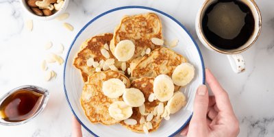 Lívance s mandlemi a banány na talíři, vedle je v nádobě čekankový sirup a v hrnku čekankový nápoj