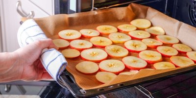 Ruka dává jablka na plechu do trouby