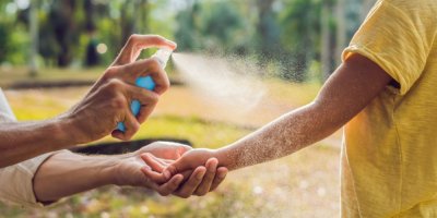 Dospělý muž aplikuje repelent na ruce chlapce