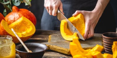 Člověk krájí dýni na prkénku