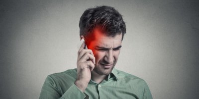Muž drží telefon u hlavy a trpí radiací z telefonu