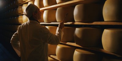 Muž stojí u regálu plného velkých kol sýru