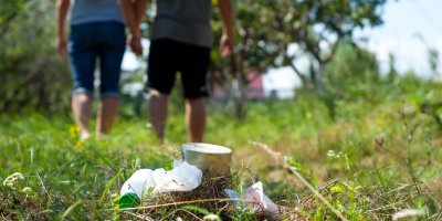 Dva lidé odchází od odpadků pohozených v přírodě