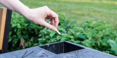 Ruka drží cigaretu nad popelníkem