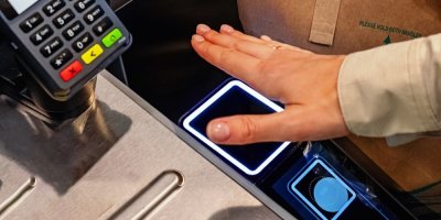Žena přikládá ruku k platebnímu přístroji