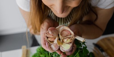 Žena drží palici česneku v ruce