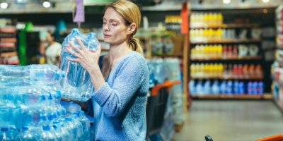 Žena bere balenou vodu v supermarketu z palety