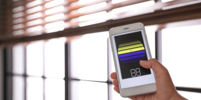 Ruka ovládající chytré žaluzie prostřednictvím mobilního telefonu