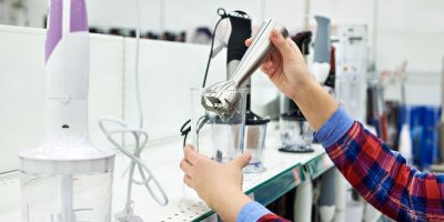 Žena vybírá tyčový mixér v obchodě