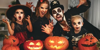 Rodiče s dvěma dětmi v halloweenských kostýmech nad dýněmi