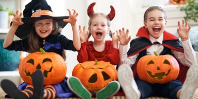 Tři děti v kostýmech čarodějnice, čerta a upíra držící dýně