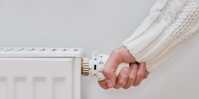 Ruka nastavuje teplotu na radiátoru