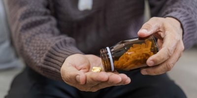 Člověk si sype doplňky stravy z lahvičky do dlaně