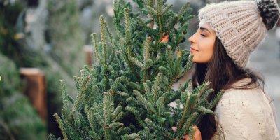 Žena v kulichu si čichá k vánočnímu stromku