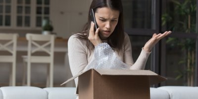 Znepokojený člověk má před sebou otevřenou krabici a u ucha má mobil