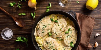 Kuřecí prsa ve smetanové česnekové omáčce na litinové pánvi na dřevěném stole