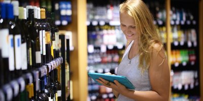 Žena se dívá do tabletu v obchodě s vínem