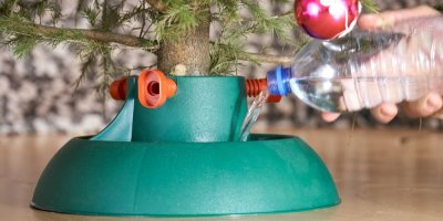 Člověk zalévá stromeček do stojanu