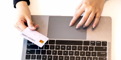 Žena sedí u notebooku a chystá se platit kartou online