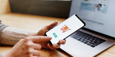 Žena drží v ruce mobil a chystá se provést nákup přes e-shop