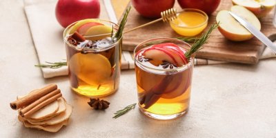 Dvě sklenice se ciderem, jablky, skořicí a medem