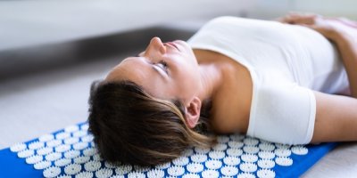 Žena leží na akupresurní podložce