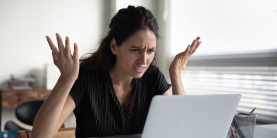 Žena sedí u notebooku a rozhazuje rukama