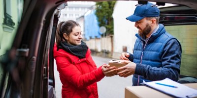 Žena přebírá balíček od dopravce