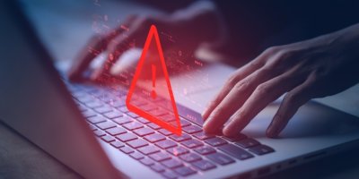 Člověk píše na klávesnici, na které svítí velký rudý vykřičník