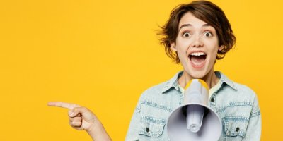 Žena se raduje, v ruce megafon, žluté pozadí