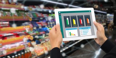 Maloobchodník drží tablet a používá technologii rozšířené reality k monitoringu dat o nabízených produktech