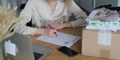 Člověk vyplňuje reklamační formulář, na stole je notebook, krabice a oblečení