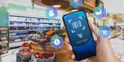 Ruka s mobilem v obchodě se zeleninou