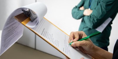 Člověk zapisuje údaje na papír v deskách