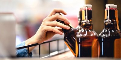 Ruka v obchodě sahá po lahvi piva