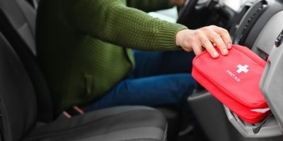 Člověk vytahuje autolékárničku z přihrádky v autě