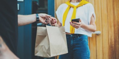 Kurýr předává ženě papírovou tašku