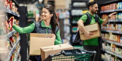 Usmívající se zaměstnanci obchodu doplňují zboží