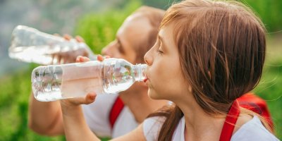 Dítě a otec pijou vodu z PET lahve