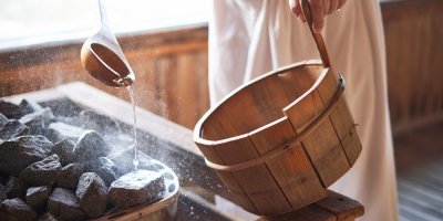 Muž nalévá v sauně na horké kameny vodu