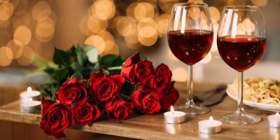 Dvě sklenice s červeným vínem, růže, svíčky