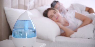 Spící pár v ložnici, zvlhčovač vzduchu na nočním stolku