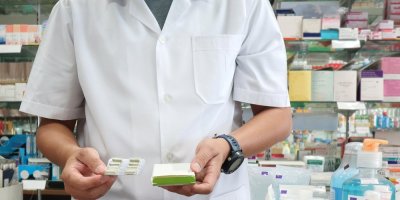 Lékárník, který drží v ruce krabičku s léky